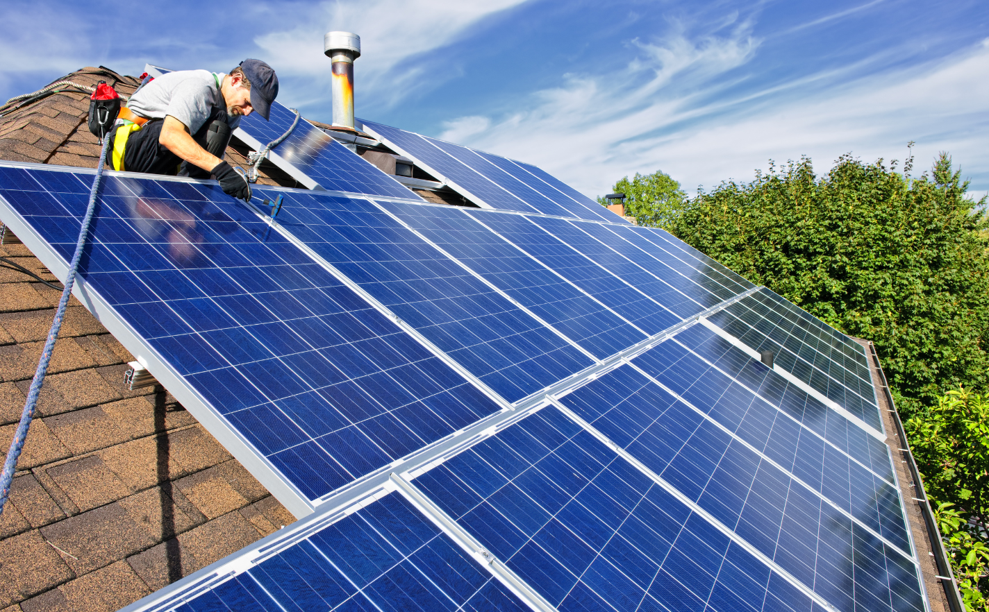 Image of person fixing solar panels to house roof